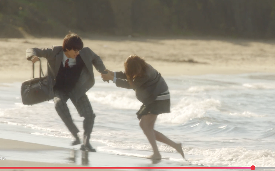 Two high school students run away from the waves on the beach in the movie “Your Lie in April”.